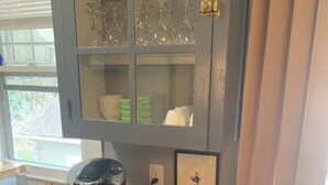 A wooden cabinet with a coffee maker and a basket of mail on top.