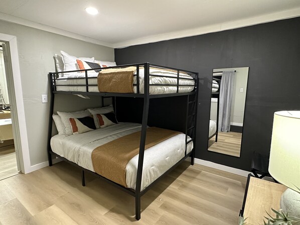 A bunk bed room with a mirror, a lamp, and a small table.
