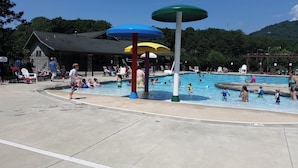 Una piscina pubblica con diverse zone dedicate al gioco acquatico e un'area salotto coperta.