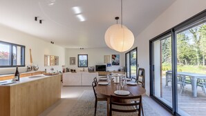 A modern kitchen with a central island, large windows, and a dining area with a round table. - L'Élégance | 115 m² | 4 + 2 guests | Design & Nature (Honfleur)