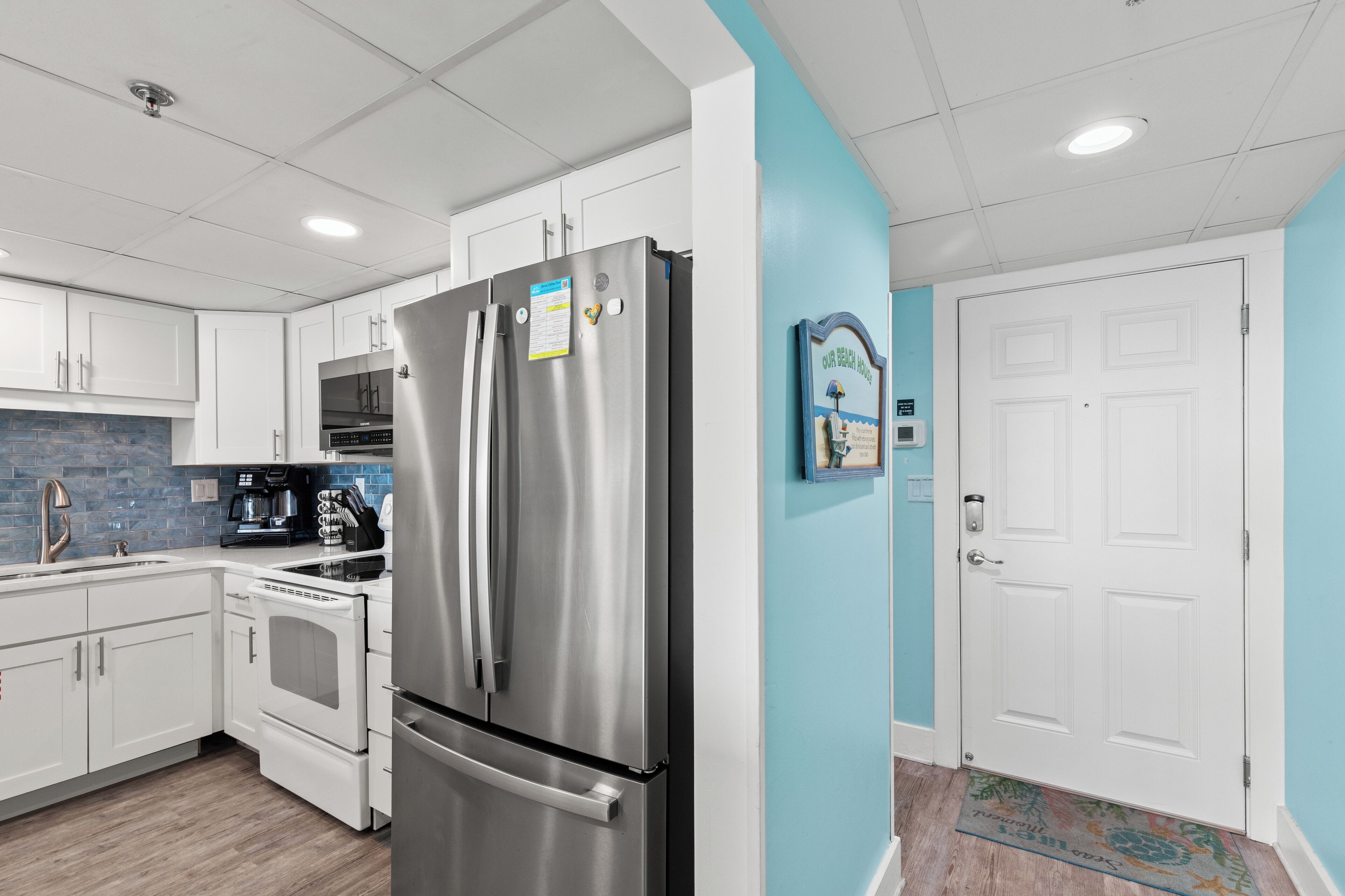 Una cocina moderna con electrodomésticos de acero inoxidable, armarios blancos y una pared de acento azul.
