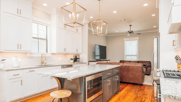 A modern kitchen with white cabinetry, a granite countertop, and stainless steel appliances.