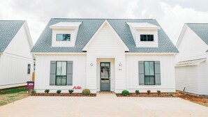 A two-story house with a front porch, a small attached garage, and a number 283 on the door.