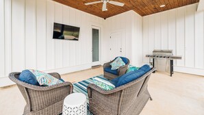 A covered outdoor area with wicker furniture, a ceiling fan, and a barbecue grill.