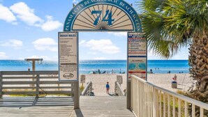 Una entrada a la playa con un cartel que indica 'Panama City Beach Public Beach Access' y 'Normas de la playa'.