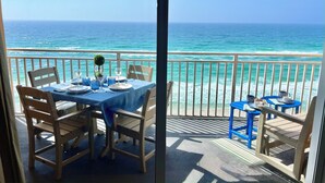 Un balcón con una mesa lista para comer, con vista al océano.