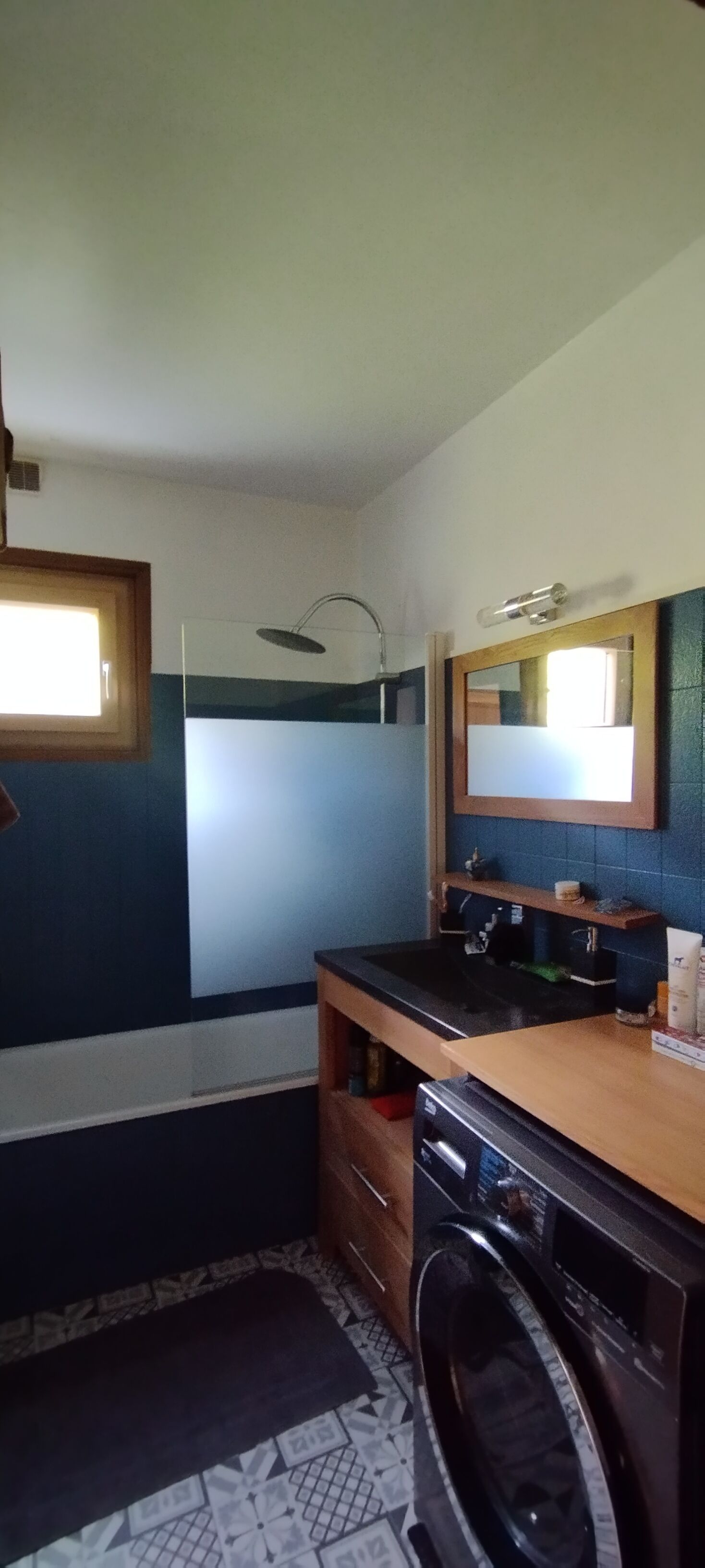 A compact bathroom with a sink, mirror, and a washing machine.