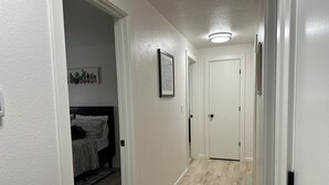 A hallway with a bed, a rug, and a door at the end. - Eugene Escape Close to Airport & Peaceful (Eugene)