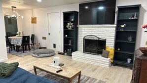 A living room with a fireplace, a dining area, and a TV. - Eugene Escape Close to Airport & Peaceful (Eugene)