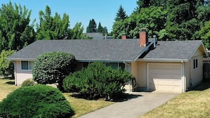 A single-story house with a garage, a driveway, and a well-maintained lawn. - Eugene Escape Close to Airport & Peaceful (Eugene)