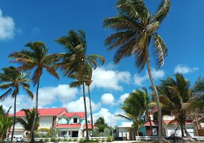A beachfront property with multiple buildings, palm trees, and a clear blue sky. - T2*** at Crystal Beach on the edge of the Saint-François lagoon. Swimming pools and beach! (Saint-François)