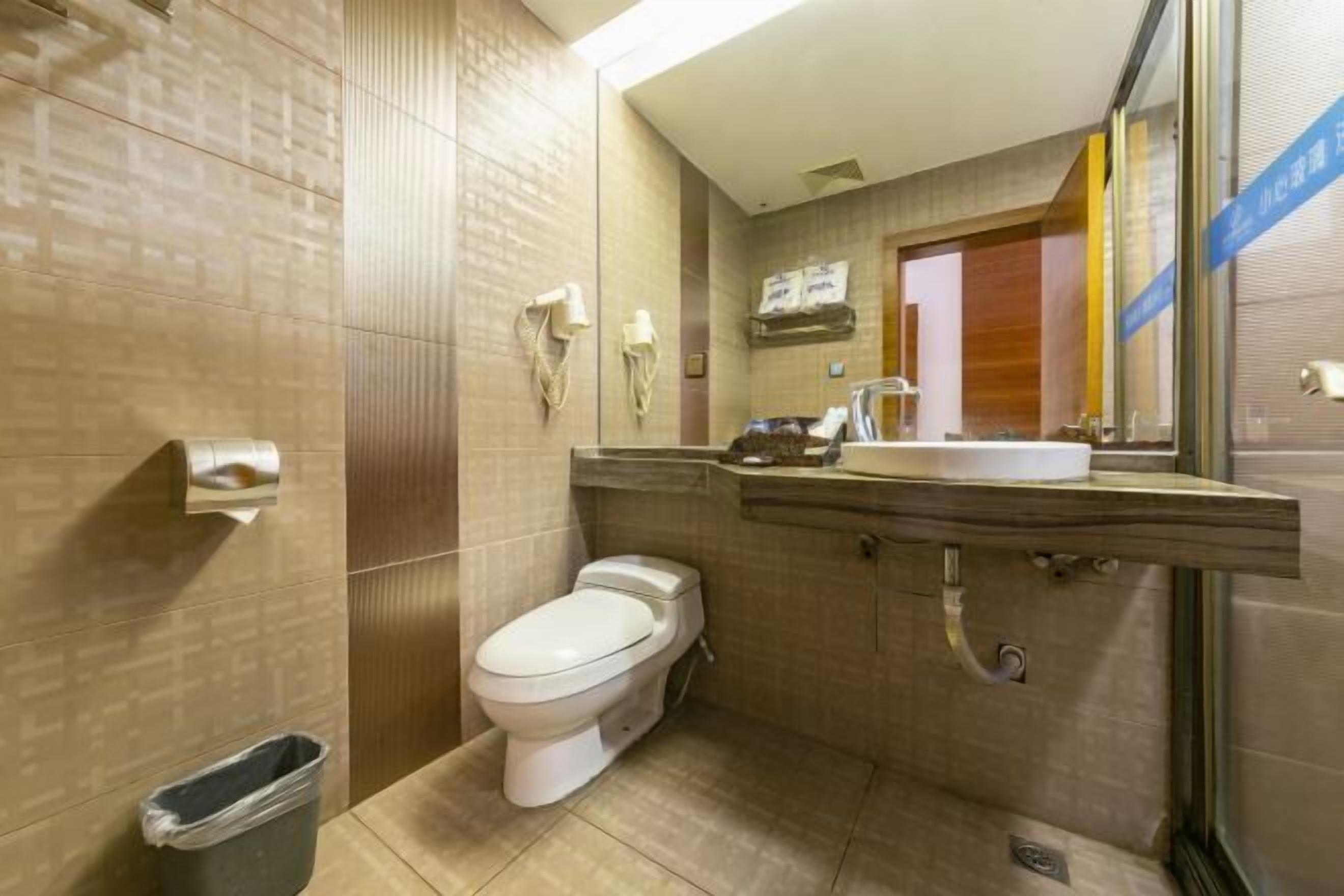 Un baño pequeño con inodoro, lavamanos y dispensador de toallas.