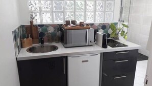 A compact kitchen with a microwave, toaster, and sink. - Cosy studio in large garden with trees, terrace with jacuzzi (Saint-Louis)