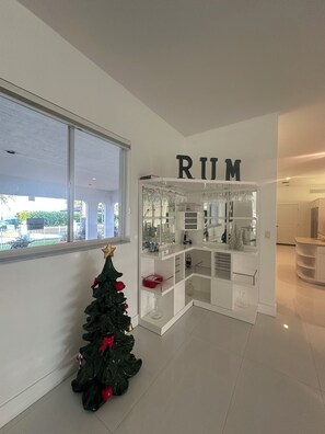 A modern interior with a glass display case labeled 'RIM' containing various items. A small Christmas tree is visible in the foreground. - 3-bedroom in Davie . WiFi, AC. Pool ,near to Sawgrass Mall, Hard Rock ,F Garden, (Davie)