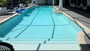 A covered swimming pool with lounge chairs and a glass ceiling.