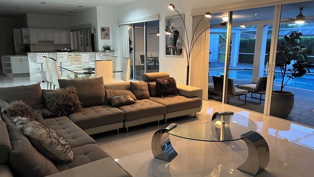A modern living room with a sofa, a glass coffee table, and a view of the outdoor patio.