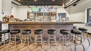 A bar area with a counter, multiple stools, and hanging light fixtures.