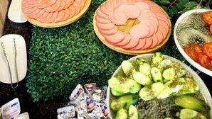Un bufé con una variedad de alimentos, incluyendo carnes en rodajas, verduras y frutas.