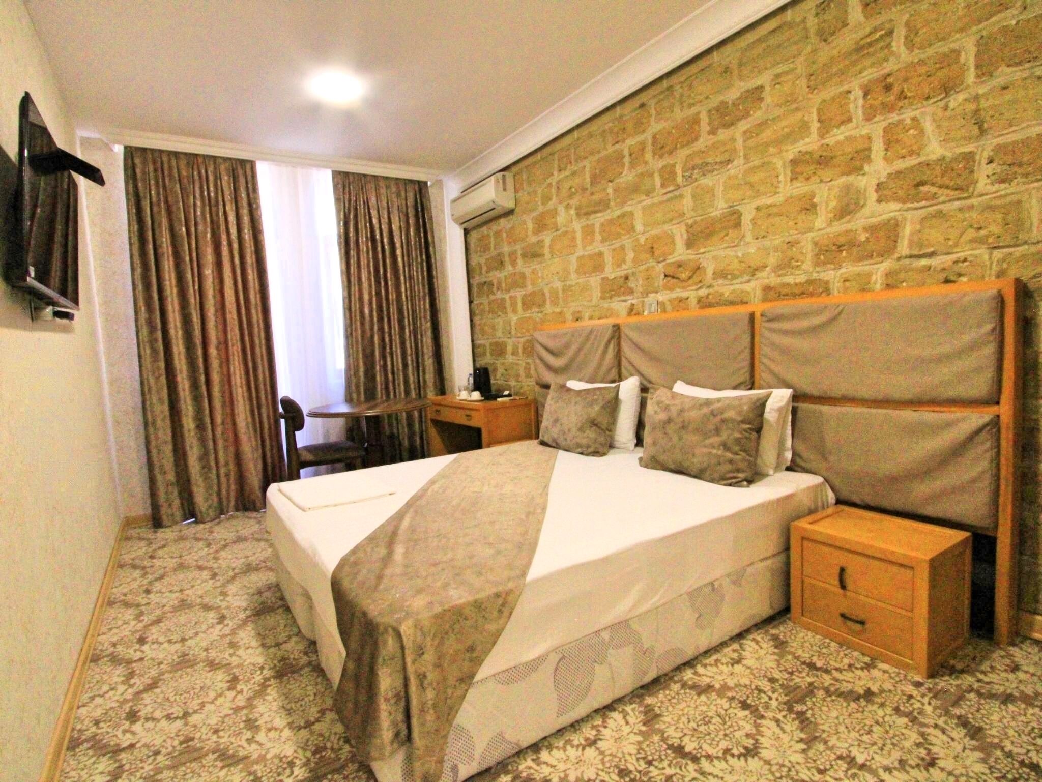 A hotel room with a large bed, a wooden headboard, a desk, and a chair.