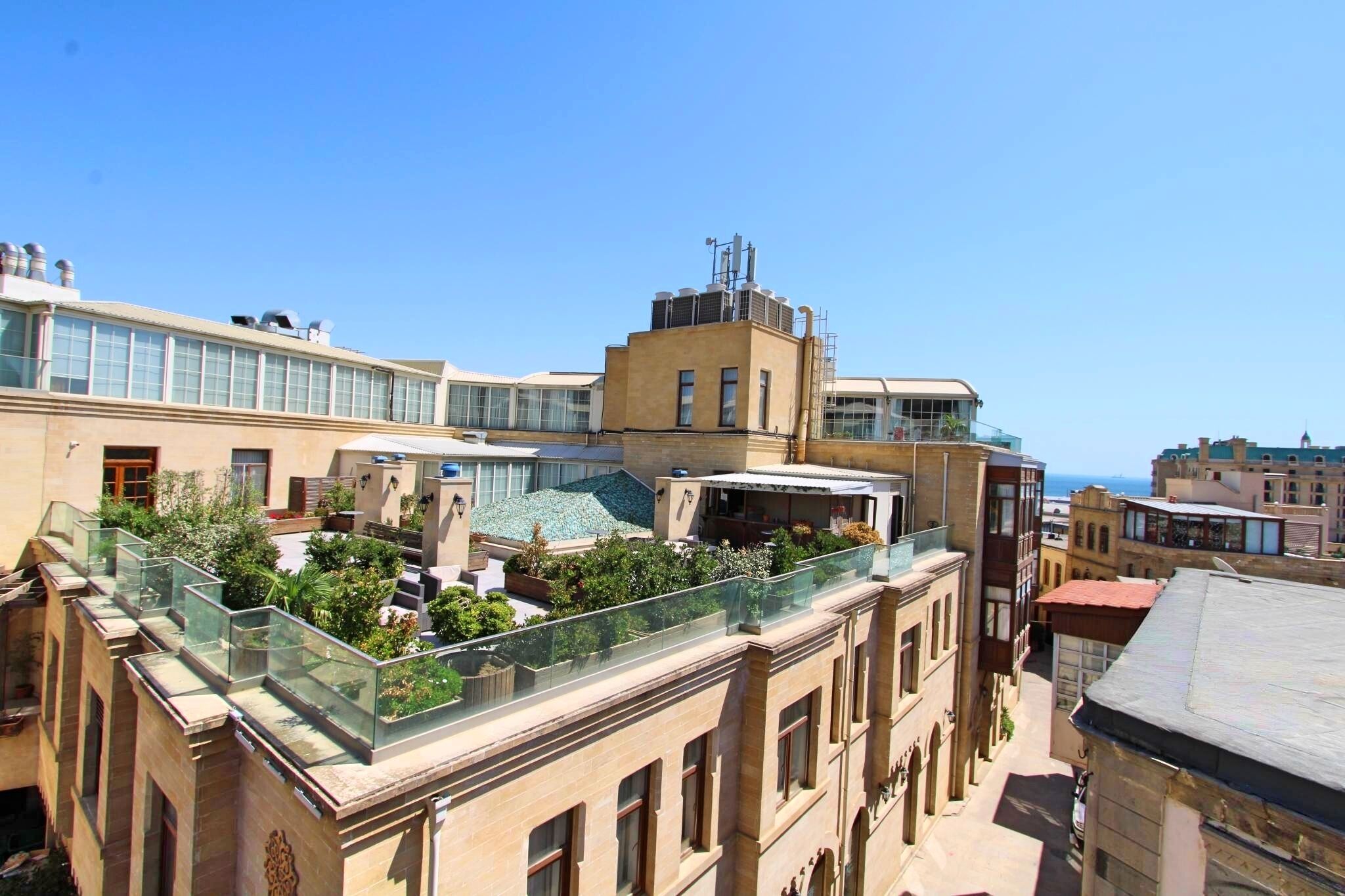 Une terrasse sur le toit avec des garde-corps en verre, une piscine et une végétation luxuriante tout autour.