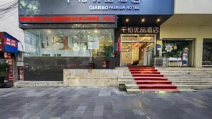QIANBO PREMIUM HOTEL har en tydlig entré, en trappa som leder upp till entrén och en väl synlig skylt.