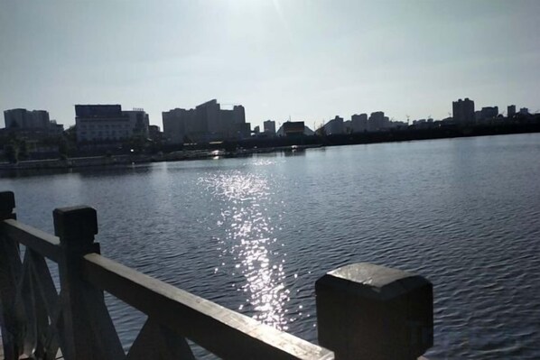 A calm river with a wooden railing in the foreground and a city skyline in the background. - Anshun Qianbai Premium Hotel (Municipal Government Anshun Ancient City Branch) (Anshun)