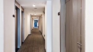 En hotellkorridor med ett heltäckningsmatta på golvet, trädörrar och en skylt som visar rummens nummer.