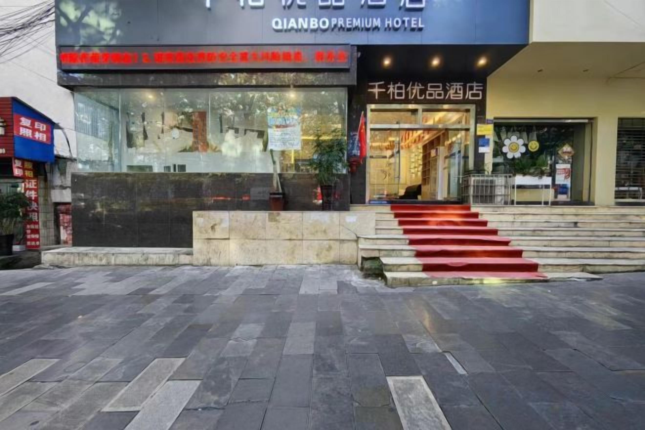 A hotel entrance with a staircase leading up to the door, a reception desk, and a sign indicating the hotel name.