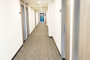 A hotel hallway with carpeted floors, doors on both sides, and a blue door at the end. - Anshun Qianbai Premium Hotel (Municipal Government Anshun Ancient City Branch) (Anshun)