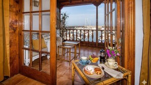 Varanda de madeira com mesa posta para o café da manhã, vista para um areal e um quarto em estilo japonês tradicional com portas de correr.