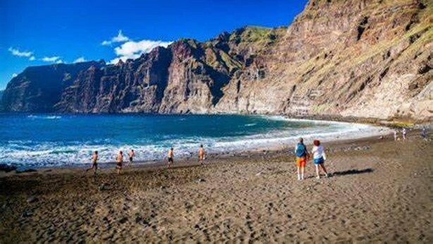 Uma praia com falésias rochosas e águas azul-claras.