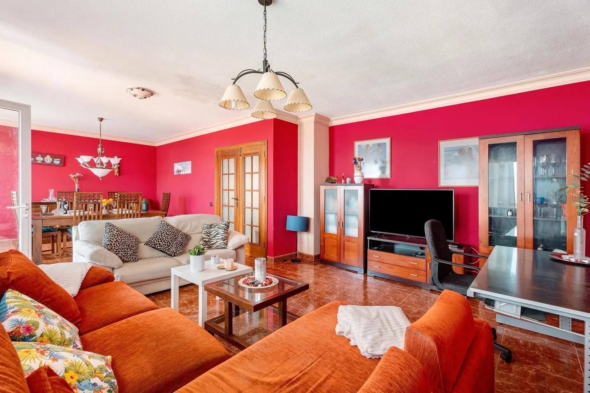 Een woonkamer met een bank, salontafel, televisie, en een eethoek met stoelen en een tafel.