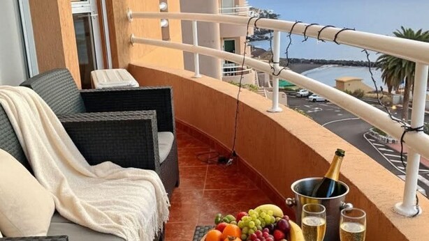 A balcony with wicker furniture, a fruit bowl, and champagne glasses.