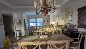 Ein Essbereich mit einem Holztisch und Stühlen, einer Chandelüster und einer Küche im Hintergrund.