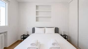 Een hotelkamer met een bed, twee nachtkastjes, een radiator en een raam.