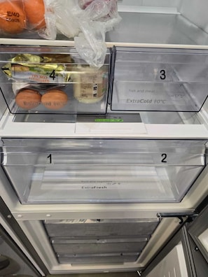 A refrigerator with labeled compartments for fish and meat, fruit and vegetables, and a section marked as ExtraCold.