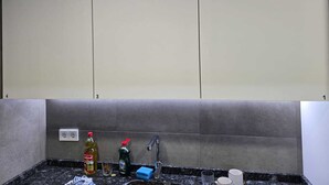 A kitchen with a marble countertop, a faucet, and various kitchen items like bottles and a sponge.