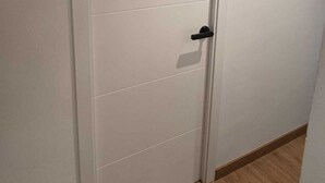 A white door with a black handle and a small rectangular cutout.