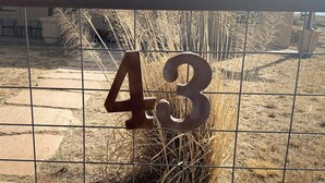 Una cerca metálica con el número 43, rodeada de hierba seca y un edificio al fondo.