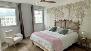 A bedroom with a bed, a chair, a nightstand, and a ceiling fan.