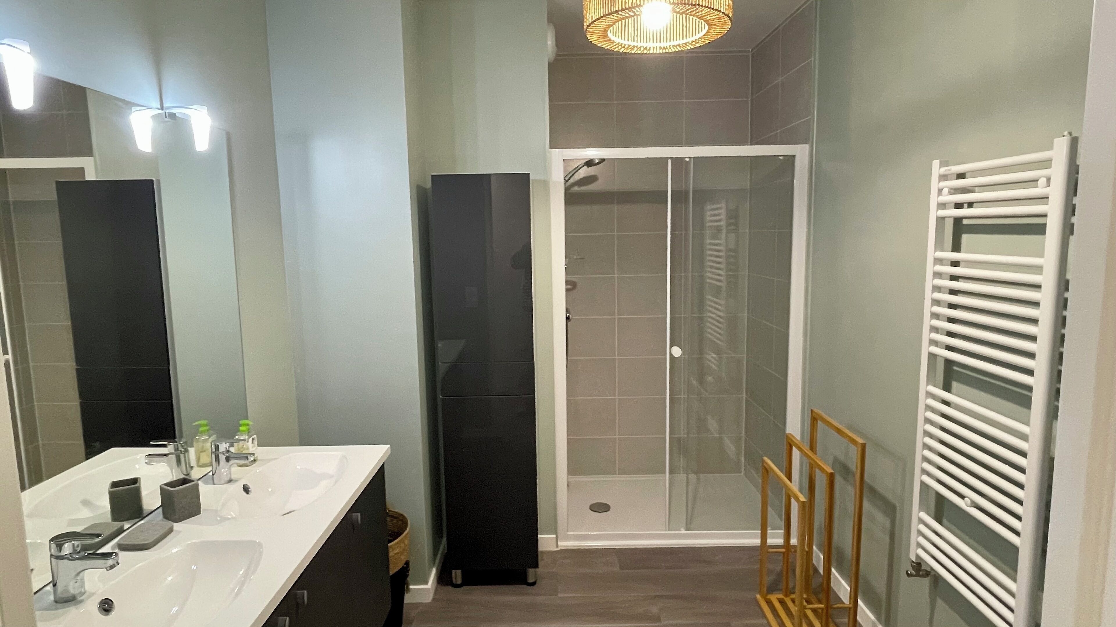 Uma casa de banho moderna com lavatório branco, espelho e cabine de duche.