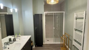 A modern bathroom with a white sink, mirror, and shower enclosure.