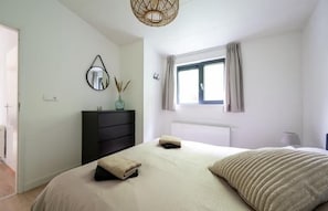 Relax in a serene bedroom with a large bed, dresser, and natural light.