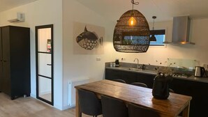 A modern kitchen with a wooden dining table, black chairs, and a hanging light fixture. - Luxury holiday cottage, stunning views, and hot tub. (Pingjum)