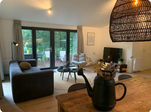 Relax in this stylish living room with a sofa, coffee table, and unique vase, leading to a patio with outdoor seating.