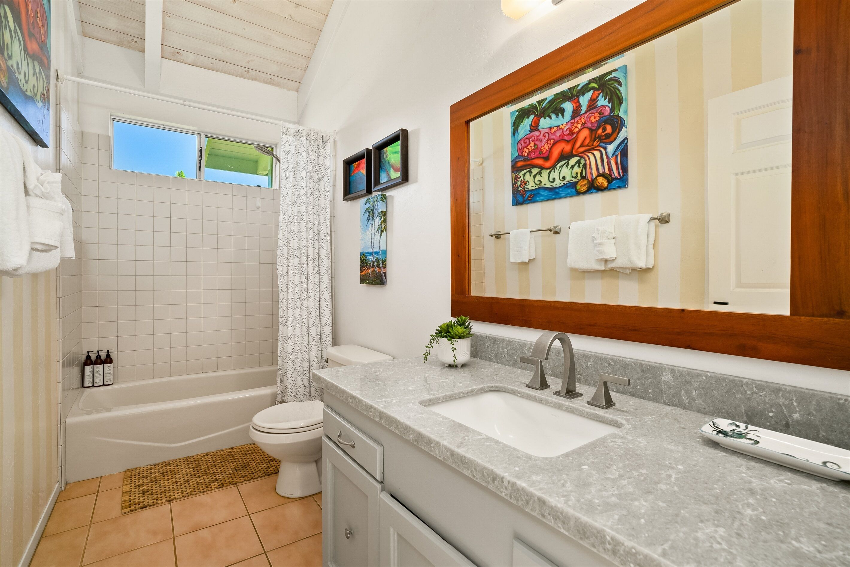 Ein modernes Badezimmer mit Badewanne, Toilette und Waschbecken. Handtücher hängen an der Wand und auf dem Waschtisch steht ein Blumentopf.