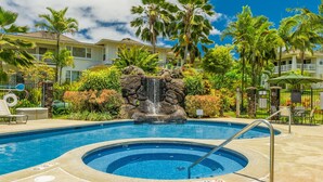 Una piscina con hidromasaje, rodeada de exuberante vegetación y palmeras.