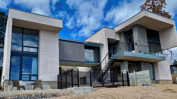 A modern two-story house with large windows, a balcony, and a staircase leading to an upper level. - Modern Private Casita • Bright, Quiet, Minutes to LANL & Trails (Los Alamos)