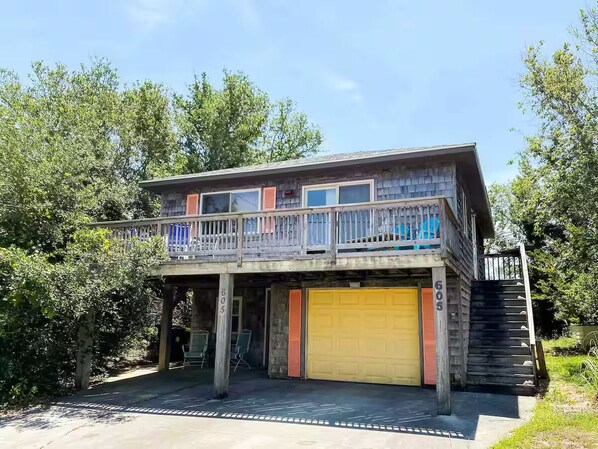Une maison à deux étages dotée d’un balcon, d’un garage et d’un escalier menant à l’étage supérieur.