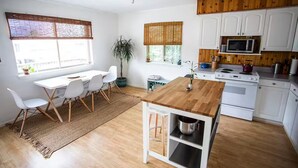 Eine moderne Küche mit weißen Schränken, einer Holz Arbeitsplatte und einer eingebauten Mikrowelle.